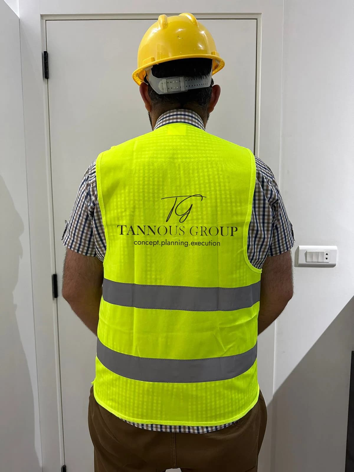 Branded Tannous Group high-visibility site vest, back with TG logo